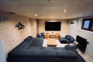 uma sala de estar com um sofá e uma televisão de ecrã plano em House type chalet - sauna and balneo - 14 pers em Gérardmer