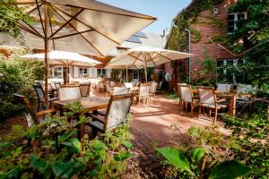 eine Terrasse mit Tischen, Stühlen und Sonnenschirmen in der Unterkunft Meyers Hofcafe in Isenbüttel