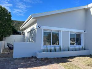 a white house with a chair in front of it at 34.4 Degrees South Studio Apartment in Agulhas