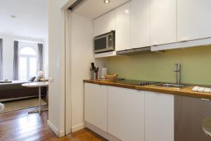 uma cozinha com armários brancos e um lavatório em Chic 1-bed flat with balcony, view and workspace, 5mins to Santa Justa Lift em Lisboa