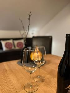 two wine glasses sitting on a wooden table with a bottle at Pension Steinkogel in Sankt Leonhard im Pitztal