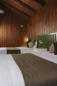 two beds in a room with wood paneling at Lauraceas Lodge in San Gerardo de Dota