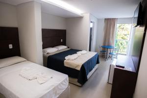 a hotel room with two beds and a table at Pousada Orla dos Corais in Maragogi
