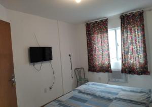 a bedroom with a bed and a television on the wall at Residencial Louise in Balneário Camboriú