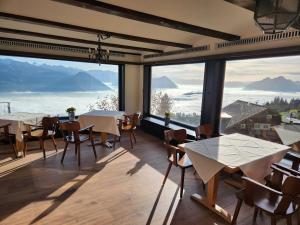 a restaurant with tables and chairs and large windows at Hotel Bergsonne Rigi in Rigi Kaltbad