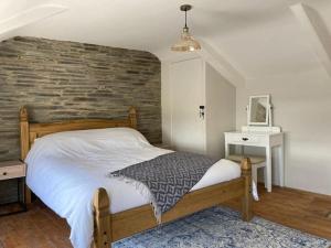 1 dormitorio con cama y pared de ladrillo en Restored, beautiful cottage, North Cornwall, en Delabole