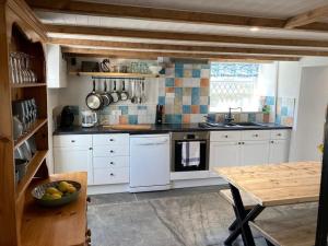 cocina con electrodomésticos blancos y mesa de madera en Restored, beautiful cottage, North Cornwall, en Delabole