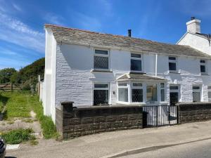 una casa blanca al lado de una calle en Restored, beautiful cottage, North Cornwall, en Delabole