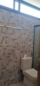 a bathroom with a toilet and a tile wall at Suite Ilhabela - com varanda e vista panorâmica in Ilhabela