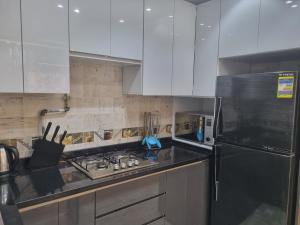 eine Küche mit weißen Schränken und einem schwarzen Kühlschrank in der Unterkunft Elite apartment in Mohandessin in Kairo