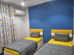 2 Betten in einem Zimmer mit blau und gelb in der Unterkunft Elite apartment in Mohandessin in Kairo