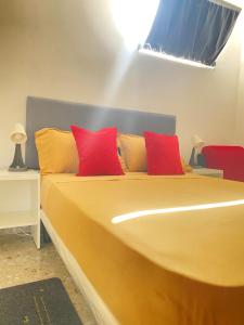 łóżko z czerwonymi i żółtymi poduszkami w pokoju w obiekcie Best Rooms- Quarto 4 Plateau w mieście Praia