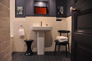La salle de bains est pourvue d'un lavabo blanc et de deux tabourets. dans l'établissement Alba Opéra Hôtel, à Paris