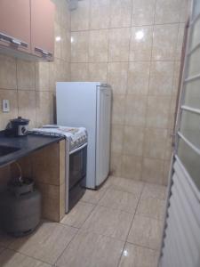 a kitchen with a white refrigerator and a stove at Kitnet completa in Guaratinguetá