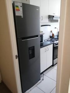 una nevera negra en una cocina junto a una estufa en Departamento de 3 habitaciones frente a la universidad de Talca, en Talca