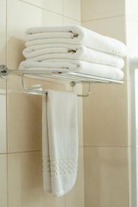 um monte de toalhas estão num toalheiro na casa de banho em Luds Comfort Hotel em Ponta Grossa