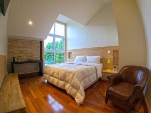 1 dormitorio con 1 cama grande y 1 silla en Austin Suites, en Campos do Jordão