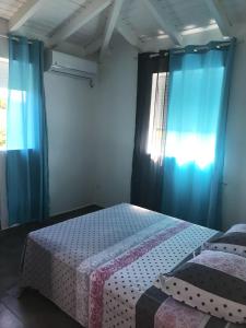 a bedroom with two beds and blue curtains at Villa enchanteresse au Moule avec piscine privée in Le Moule