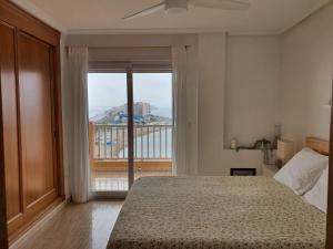 ein Schlafzimmer mit einem Bett und einem großen Fenster in der Unterkunft La Manga - Puerto y Playa - 3 dormitorios in La Manga del Mar Menor