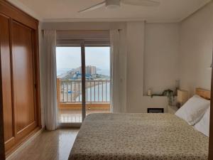 1 dormitorio con cama y ventana grande en La Manga - Puerto y Playa - 3 dormitorios, en La Manga del Mar Menor