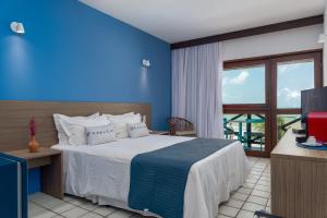 1 dormitorio con 1 cama con pared azul en Hotel Areias Belas en Maragogi