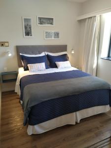 1 dormitorio con 1 cama grande con almohadas azules en Flat Charmoso Jardim Paulista en São Paulo
