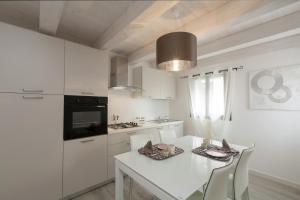 a white kitchen with a white table and chairs at Residenza Tiziano in Venice