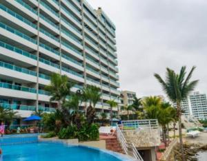 a large apartment building with a swimming pool and palm trees at Ecusuites Salinas Resort 7F Departamento Piscina in Salinas