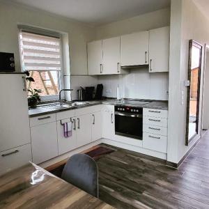 a kitchen with white cabinets and a table and a chair at LandBrise in Petersfeld