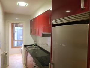 a kitchen with red cabinets and a stainless steel refrigerator at Apartamento centro Villagarcía. in Vilagarcia de Arousa +10 photos