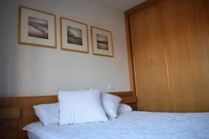 a bedroom with a bed with two pictures on the wall at Apartamento centro Villagarcía. in Vilagarcia de Arousa