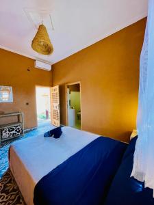 a bedroom with a blue bed and a yellow wall at Tigmi Timhar 