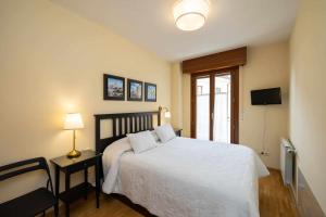 1 dormitorio con 1 cama blanca y TV en Casa benito en el corazón del casco histórico garaje incluido, en Zamora