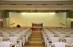 an empty lecture hall with white chairs and a podium at Garden Hotel e Eventos in Benevides