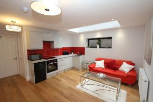 a living room with a red couch and a kitchen at Lovely One Bed Apartment-Near All Transport-Village-FreeParking in London