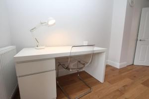een wit bureau met een lamp erop bij Lovely One Bed Apartment-Near All Transport-Village-FreeParking in Londen