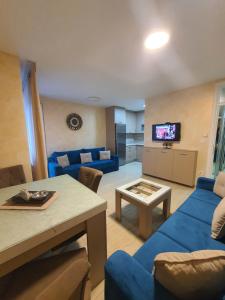 ein Wohnzimmer mit einem blauen Sofa und einem Tisch in der Unterkunft Apartman KRISTINA,Istocno Sarajevo,Vojvode Radomira Putnika 49D in Sarajevo