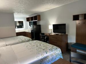 ein Hotelzimmer mit zwei Betten und einem Flachbildfernseher in der Unterkunft HomeTowne Studios by Red Roof Georgetown, KY in Georgetown
