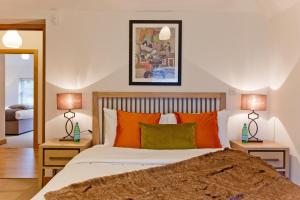 2 Bed Mews House Marylebone في لندن: غرفة نوم مع سرير مع وسائد برتقالية وأخضر