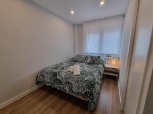 - une chambre avec un lit et une couverture noire et blanche dans l'établissement 136A Apartamento moderno en Playa San Lorenzo, à Gijón