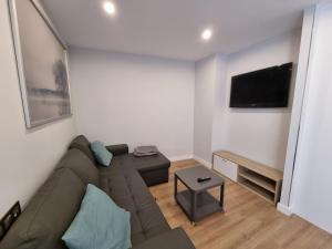 a living room with a couch and a flat screen tv at 136A Apartamento moderno en Playa San Lorenzo in Gijón