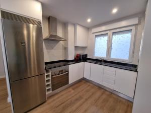 uma cozinha com armários brancos e um frigorífico de aço inoxidável em 136A Apartamento moderno en Playa San Lorenzo em Gijón