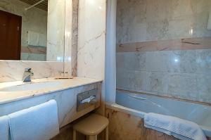 ein Badezimmer mit einem Waschbecken, einer Badewanne und einem Spiegel in der Unterkunft Hotel Am Blauen Wunder in Dresden
