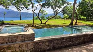 a swimming pool in a stone wall next to a lake at El Guayacan Retreat in Valle la Laguna