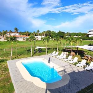 a swimming pool with chairs and a table and trees at Nomada Republic Hotel Punta Chame in Punta Chame