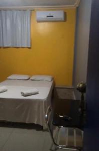 Cama en habitación con pared amarilla en Pousada Ferreira, en Aracaju