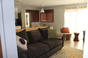 sala de estar con sofá marrón y cocina en A Gem Inn the Rockies, en Jasper