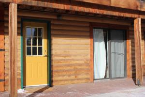 Cette cabane en bois dispose d'une porte jaune et de deux fenêtres. dans l'établissement A Gem Inn the Rockies, à Jasper
