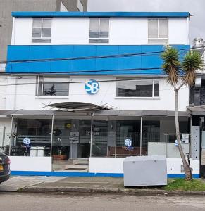 ein blau-weißes Gebäude mit einer Palme davor in der Unterkunft Stay Blue Hotel in Bogotá