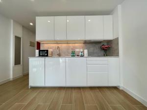 a kitchen with white cabinets and a wooden floor at Malibu Park 2115 - Ocean View in Adeje